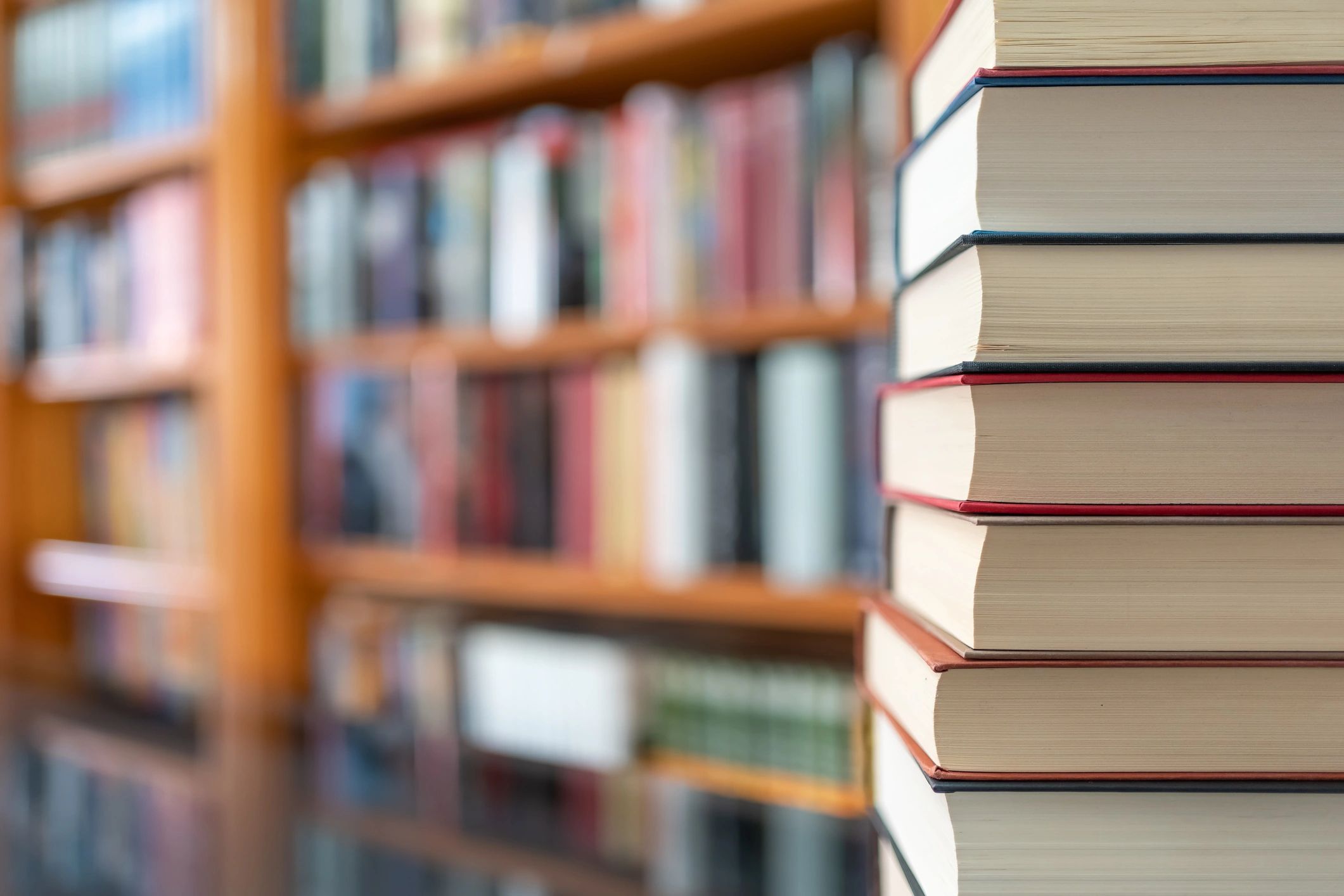 Pilha de livros com fundo de livraria, simbolizando leitura e pesquisa